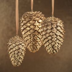 three gold pine cones hanging from strings