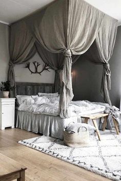 a canopy bed in a bedroom with white walls and wooden floors, along with a rug on the floor