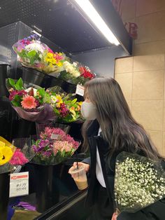 a woman wearing a face mask is looking at flowers