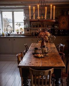 a wooden table sitting in the middle of a kitchen with candles on top of it