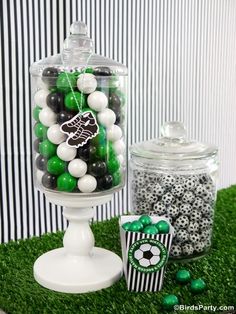 there is a large glass jar filled with green and white balls next to some black and white candies