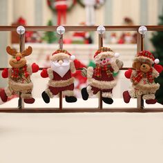 four stuffed animals hanging from clothes pins on a rack in front of a christmas tree