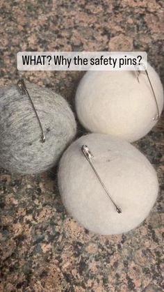 three wool balls with pins on them sitting on a granite counter top next to a piece of paper that says what? why the safety pins?