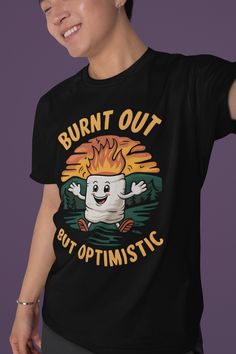 Elevate your camping wardrobe with our "Burnt Out but Optimistic" T-shirt! Featuring a whimsical marshmallow with a playful grin, flames flickering atop its head, this tee perfectly captures the spirit of adventure and resilience in the great outdoors. Made from soft, breathable fabric, it's perfect for those cozy campfire nights or hikes under the stars. Show off your love for camping and a good laugh, reminding everyone to stay cheerful, even when life gets a little toasty! Grab yours and let the good vibes roll! Product features - Shoulder tape for stability and comfort - No side seams for a sleek appearance - Ribbed collar retains shape and elasticity - Made from durable, smooth fabric - Ethically sourced 100% US cotton Care instructions - Machine wash: warm (max 40C or 105F) - Non-chl Funny Letter Print T-shirt For Outdoor, Cotton T-shirt With Funny Print For Outdoor Activities, Casual T-shirt For Camping, Funny Print T-shirt For Outdoor Activities, Black Hiking T-shirt With Letter Print, Custom Print Crew Neck T-shirt For Camping, Black T-shirt For Hiking With Letter Print, Black Letter Print T-shirt For Hiking, Casual T-shirt With Funny Print For Outdoor Activities