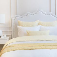 a bed with white and yellow comforters in a bedroom next to a night stand