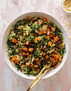 a white bowl filled with chopped vegetables next to a gold spoon on top of a table