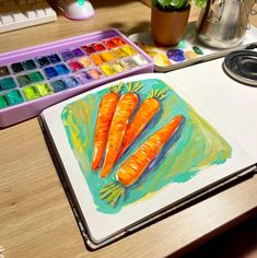 a painting of carrots on a table next to a paintbrush and watercolor palette