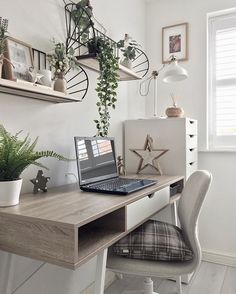 a laptop computer sitting on top of a wooden desk next to a potted plant