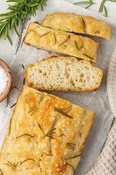 slices of bread with rosemary sprigs on top next to salt and spoons