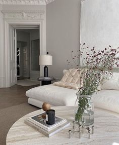 a living room filled with furniture and a white table topped with a vase full of flowers