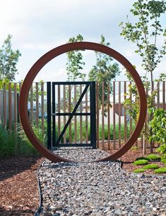 a circular metal object sitting in the middle of a gravel path next to a fence