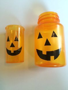 two plastic jars with jack - o'- lanterns painted on them sitting next to each other