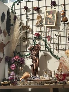 a table topped with lots of assorted items and flowers next to a wall covered in pictures