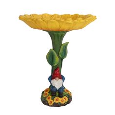 a yellow flower vase with a gnome figurine next to it