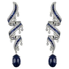 These dangling earrings exude sophistication and elegance with a perfect balance of simplicity and opulence. A striking blue sapphire takes the stage adorned with exquisitely round-cut diamonds. The design ensures a reflection of light and glamour with every move. Whether worn for a special occasion or to elevate everyday elegance, these earrings are a testament to refined taste and timeless beauty. Gross weight: 14.60 g Diamond weight: 4.03 cts Sapphire weight: 3.32 cts Sapphire weight: 10.19 c Sapphire Dangle Diamond Jewelry, Sapphire Dangle Earrings With Diamonds, Sapphire Diamond Dangle Earrings, Luxury Sapphire Dangle Jewelry, Luxury Sapphire Diamond Drop Earrings, Gold Dangling Earrings, Everyday Elegance, Dangling Earrings, Art Deco Diamond