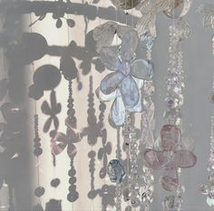 several glass beads hanging from the ceiling in front of a window with flowers on them