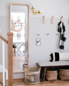 there is a coat rack on the wall next to a bench with baskets under it