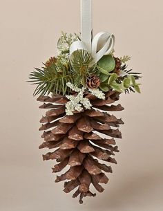 a pine cone ornament hanging from a white ribbon