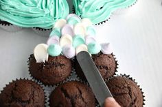 a person cutting into cupcakes with a knife