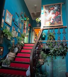 the stairs are lined with potted plants and pictures on the wall above them, along with hanging planters