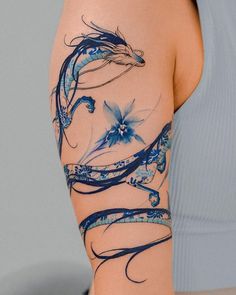 a woman's arm with blue flowers and swirls painted on it, in front of a gray background