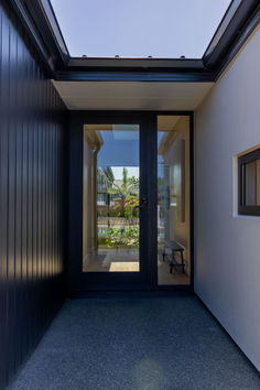 an open door leading into a house with black siding and glass doors on both sides