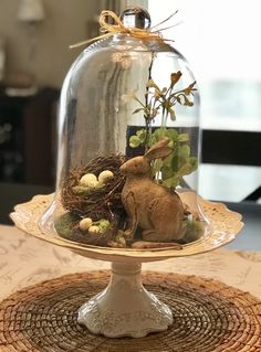 a glass clochel with an easter bunny in it sitting on top of a table