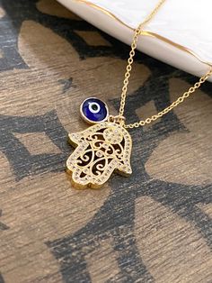 Beautifully CZ embedded gold hamsa hand pendant with Blue evil eye charm on 18K gold filled chain. HAMSA HAND Depicting the open right hand, an image recognized and used as a SIGN OF PROTECTION in many societies throughout history, the HAMSA is believed to provide defense against the evil eye. *Hamsa Hand Charm measures 20mm x 17mm ---------------------------------------- *JEWELRY CARD OPTIONS* Please indicate your choice of a message or your personals message in the 'message to seller' box as y Blue Gold Plated Charm Necklace As Gift, Gold Evil Eye Necklace As Gift, Gold Dainty Evil Eye Charm Necklace, Dainty Evil Eye Charm Necklace Gift, Gold Plated Evil Eye Charm Necklace Gift, Gold Evil Eye Pendant Charm Necklace, Spiritual Evil Eye Pendant Jewelry, Brass Evil Eye Jewelry For Gifts, Spiritual Blue Evil Eye Charm Necklace