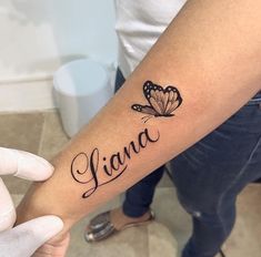 a person with a butterfly tattoo on their arm and the word livna written in cursive writing