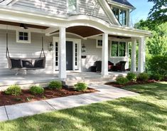 a white house with black chairs on the front porch