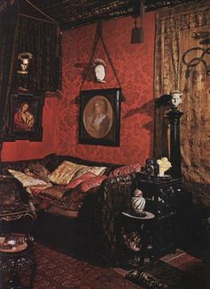 an old fashioned bedroom with red wallpaper and pictures hanging on the wall above it