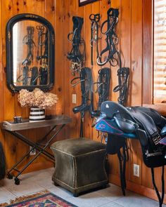 a wooden room with many horse tacks on the wall and a bench in front of it