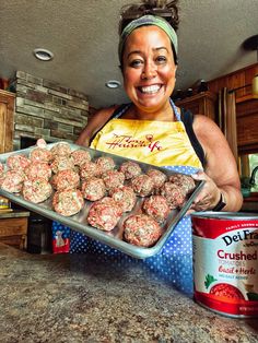 a woman holding a pan full of meatballs next to a can of canned milk