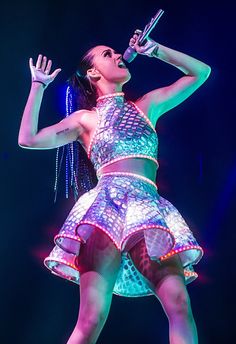 a woman in a disco outfit singing on stage with her hands up to the side