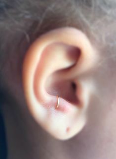 a close up of a person's ear with a tiny gold ring on it