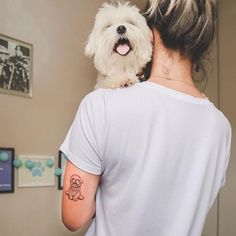 a woman holding a small white dog in her arms