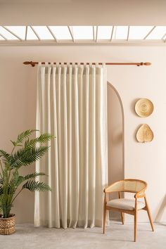 a living room with a chair, potted plant and white curtains