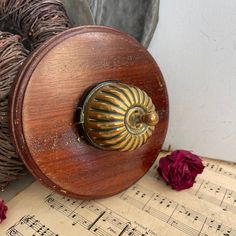 an old wooden box sitting on top of sheet music with red flowers in the background