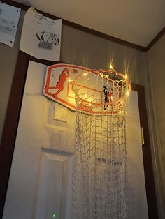 a basketball hoop with lights hanging from it's side in front of a door