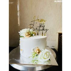 a birthday cake with white flowers and gold decorations