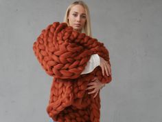 a woman is holding a large chunky blanket