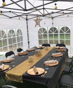 a table set up with plates and napkins under a tented area for an event