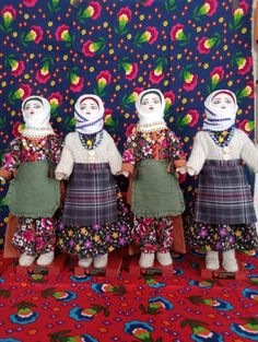 three dolls are standing in front of a colorful wall