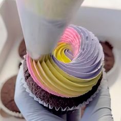 a cupcake being made with colored frosting and icing on top of it