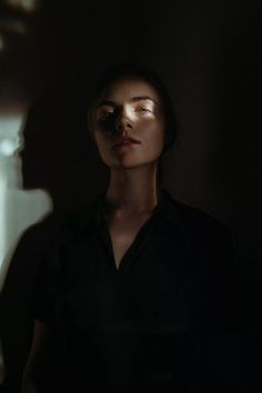 a woman standing in the dark with her eyes closed