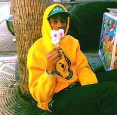 a young man sitting on the sidewalk eating a donut with a pacifier in his mouth