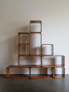 a wooden shelf sitting on top of a floor next to a wall with shelves in the shape of rectangles