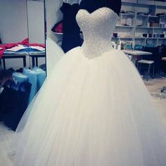 a white wedding dress is on display in a room with other clothes and accessories behind it