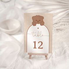 a table number with a brown teddy bear on it's head and the date is twelve