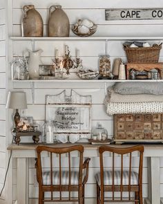 two wooden chairs sitting next to each other in front of a shelf filled with items